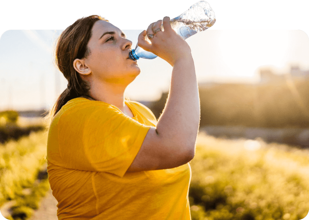 a woman drinking from a water bottle while exercising